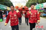 图为民众扛着烤猪前来祭祀。　胡雁　摄 - 广西新闻