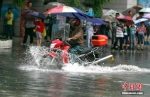 6月12日，贵阳市民骑摩托车在积水路段行驶。中新社记者 贺俊怡 摄 - 广西新闻网