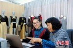 谭湘光和徒弟范丽华在商讨将时尚元素融入服装设计中。　蒋雪林 摄 - 广西新闻