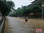 8月14日，受流域内持续强降雨影响，广西柳州市融水苗族自治县融江河水暴涨，县城老城区被淹，居民只得乘船出行。这是融水县今夏第二次遭遇洪水袭击，距离上次被淹仅过了一个半月。据融水县防汛办信息，8月14日16时，融水水文站水位为111.65米（警戒水位10d6.6米）。目前，水位仍在上涨，柳州市已经启动防洪Ⅳ级应急响应。图为民众冒雨在洪水中跋涉。蒙鸣明 摄 - 广西新闻